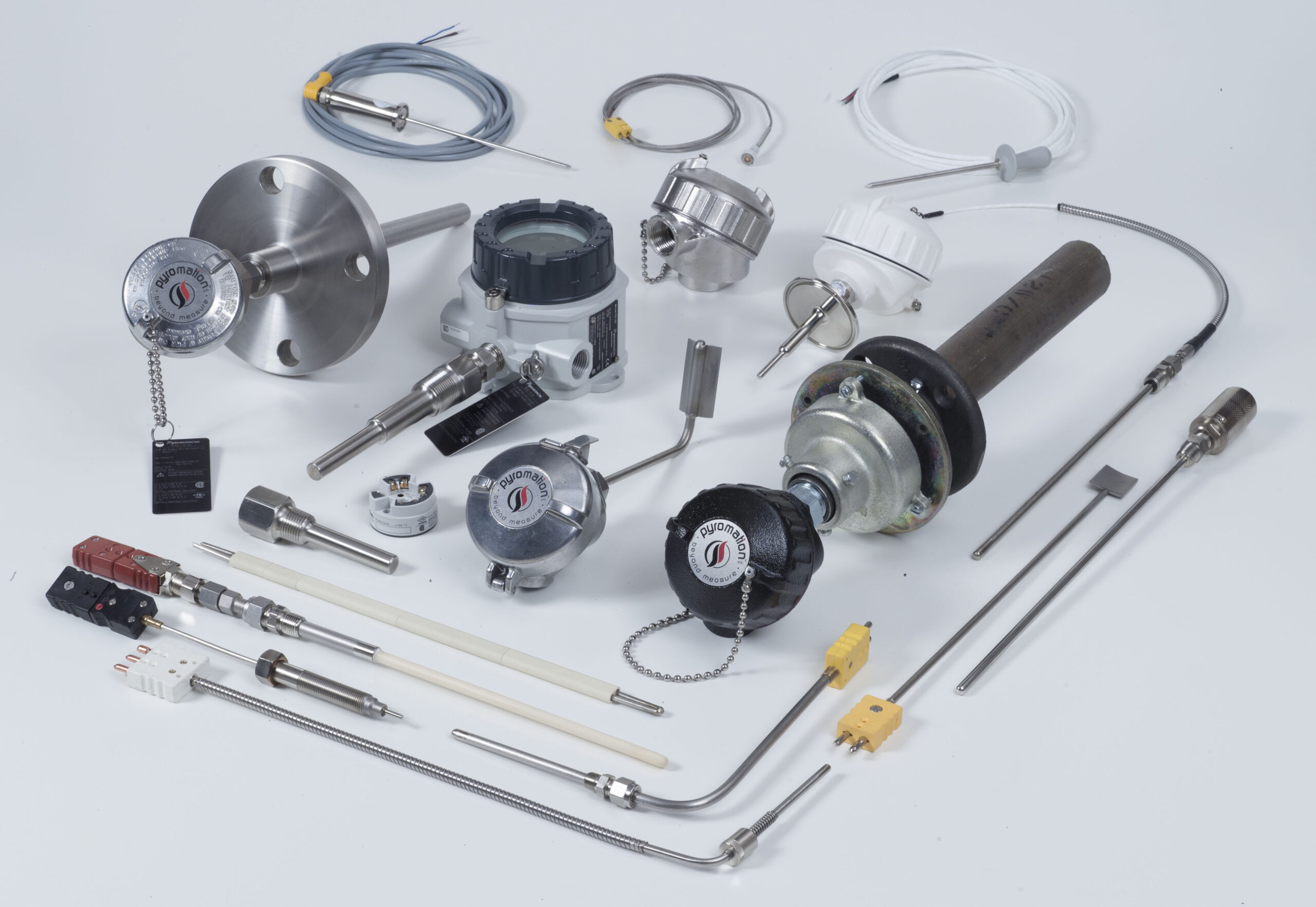Assorted industrial sensors, probes, and cables arranged on a white surface for a parts collection photo.